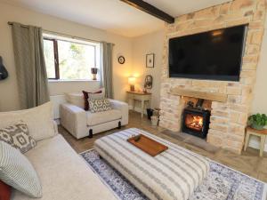 a living room with a stone fireplace with a flat screen tv at Yew Tree Cottage in Wigton