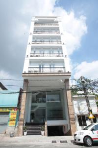 a tall white building with a car parked in front at Gia Hoa Airport Hotel in Ho Chi Minh City