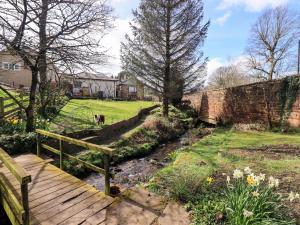a wooden walkway in a garden with a dog in a yard at Yew Tree Cottage in Wigton