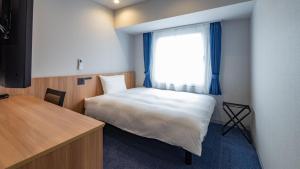 a bedroom with a bed and a window with blue curtains at Toyoko Inn Kure-eki in Kure