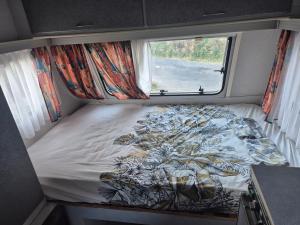 a bed in a small room with a window at Caravane dans les Cévennes in Saint-Germain-de-Calberte