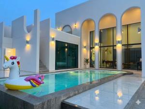 a pool with a unicorn float in front of a house at Nacha Pool Villa Cha-am in Cha Am