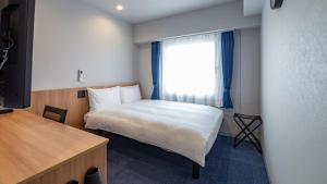 a small bedroom with a bed and a window at Toyoko Inn Kure-eki in Kure