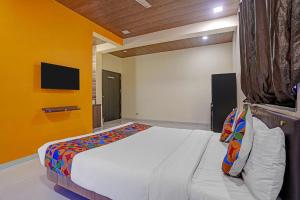 a bedroom with a large bed with a yellow wall at FabHotel Aaryras Heritage Resort in Mahabaleshwar