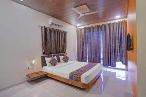 a bedroom with a bed and a window with curtains at FabHotel Aaryras Heritage Resort in Mahabaleshwar +24 photos