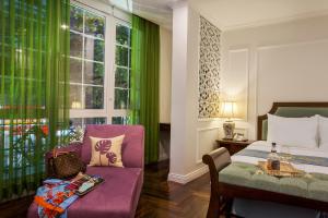 a bedroom with a bed and a chair and a window at Maro Hotel in Hanoi