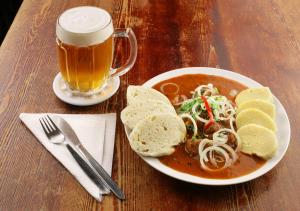 a plate of soup and bread and a cup of beer at Penzion Na Louži in Český Krumlov