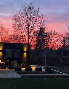 a house with a tree in front of a sunset at Cosy guesthouse in peaceful garden surroundings in Silkeborg