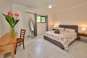 a bedroom with a bed and a table and a vase of flowers at Malanda Falls Retreat in Malanda