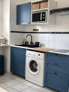 a kitchen with a washing machine and blue cabinets at T2 POMPERTUZAT Calme avec parking in Pompertuzat
