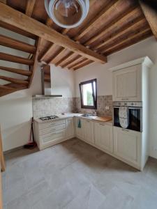 a large kitchen with white cabinets and a ceiling at Casa Lori in Fauglia