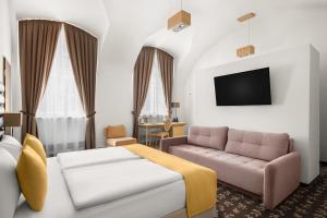a hotel room with a couch and a tv at Buda Castle Hotel Budapest in Budapest