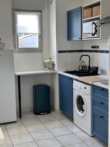 a kitchen with blue cabinets and a washing machine at T2 POMPERTUZAT Calme avec parking in Pompertuzat +4 photos