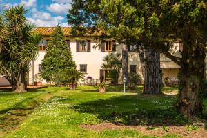a large white house with trees in the yard at Podere Magnolia in Pisa