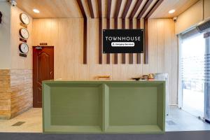 a large green counter in a room with two clocks at Super Townhouse by OYO Cosmo Mall Zirakpur Formerly R K Residency in Zirakpur