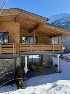 ein Holzhaus mit einer Terrasse im Schnee in der Unterkunft Alprocks Alvaresort in Bichlbach