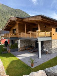 ein großes Holzhaus mit einer Terrasse darauf in der Unterkunft Alprocks Alvaresort in Bichlbach
