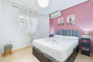 a bedroom with a large bed and a pink wall at Playa del Pinet 2 in La Marina