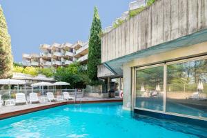a swimming pool in front of a building at SOWELL HOTELS Ardèche in Grospierres