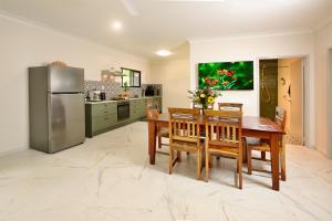 a kitchen with a table and a stainless steel refrigerator at Malanda Falls Retreat in Malanda