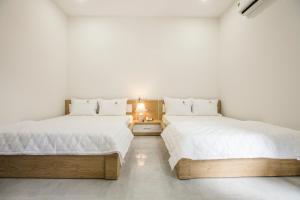 two beds in a room with white walls at Lys Hotel in Buon Ma Thuot