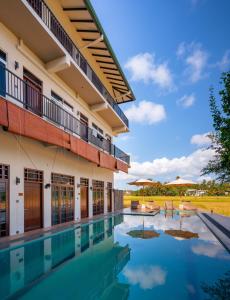 a swimming pool in front of a building with tables and umbrellas at Serene Park Hotel By Ark in Tissamaharama