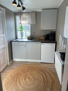 a kitchen with white cabinets and a rug on the floor at Guesthouse Holmen in Färgelanda