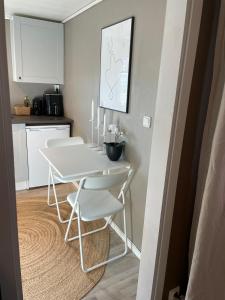 a small kitchen with a white table and white chairs at Guesthouse Holmen in Färgelanda +17 photos