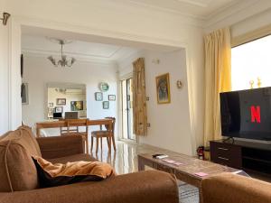 a living room with a couch and a tv at Maison de Lama - Expat friendly, AirCon, Garden access in Cairo