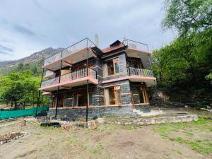 a large house with a balcony on top of it at Tirthan Villa Homestay in Banjār