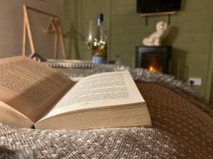 an open book on a bed with a wine glass at Cwt Gafr Bach in Pwllheli