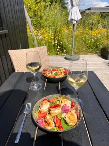 a table with two plates of food and two glasses of wine at Cosy guesthouse in peaceful garden surroundings in Silkeborg