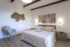 a white bedroom with a bed and a chair at Raphael's Boutique Stay in Palau