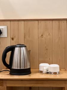 a tea kettle and two cups on a wooden table at Tirthan Villa Homestay in Banjār