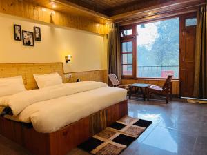 a bedroom with a bed and a table and a window at Tirthan Villa Homestay in Banjār