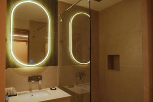 a bathroom with a sink and a shower with two mirrors at Metta Shaanti Hotel Shravasti in Khargupur +42 photos