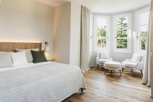 a white bedroom with a bed and two windows at Sant Patrici Hotel in Ferreries +32 photos