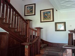 a hallway with wooden stairs and paintings on the wall at Belle Vue in Queenstown +1 photo