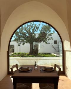 a dining room with a table with a tree in the background at Masseria Mezzamira in Pezze di Greco +5 photos