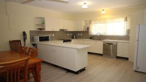 a kitchen with white cabinets and a table and a refrigerator at Del Haven Holiday House in Arcadia