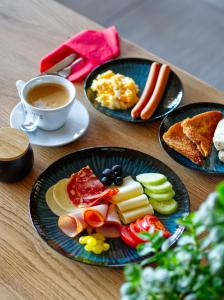 a table with three plates of food and a cup of coffee at Hotel Tor Kielce in Kielce