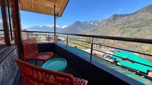 a balcony with two chairs and a view of the mountains at Romantic loft with mountain view in manali in Haripūr