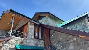 a stone house with wooden doors and a balcony at Romantic loft with mountain view in manali in Haripūr +2 photos