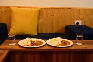 two plates of food on a wooden table at Romantic loft with mountain view in manali in Haripūr