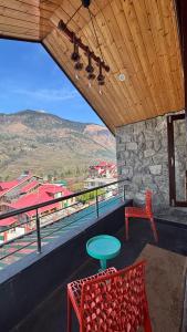 a table and chairs on a balcony with a view at Romantic loft with mountain view in manali in Haripūr