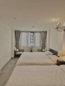 a white bedroom with two beds and a couch at PHAM Homes in Hai Phong
