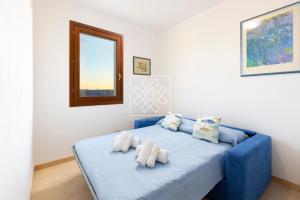 a bedroom with a blue bed with towels on it at Villino Joy in Stintino