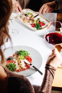 a woman sitting at a table with plates of food and a glass of wine at Alpin Peaks in Turracher Hohe +71 photos