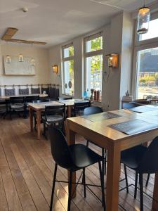 a restaurant with wooden tables and chairs and windows at Bed & Breakfast d'Ouwe Smidse in Kamperland