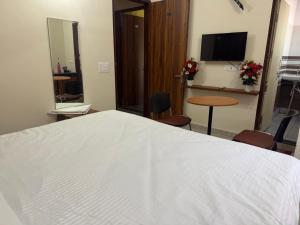 a bedroom with a white bed and a table and a television at JMD Zoom Plaza Hotel in Farrukhnagar